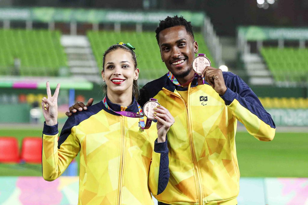 A atleta Lorena Spoladore e seu guia posam com suas medalhas nos Jogos Parapanamericanos Lima 2019. Fim da descrição. 
