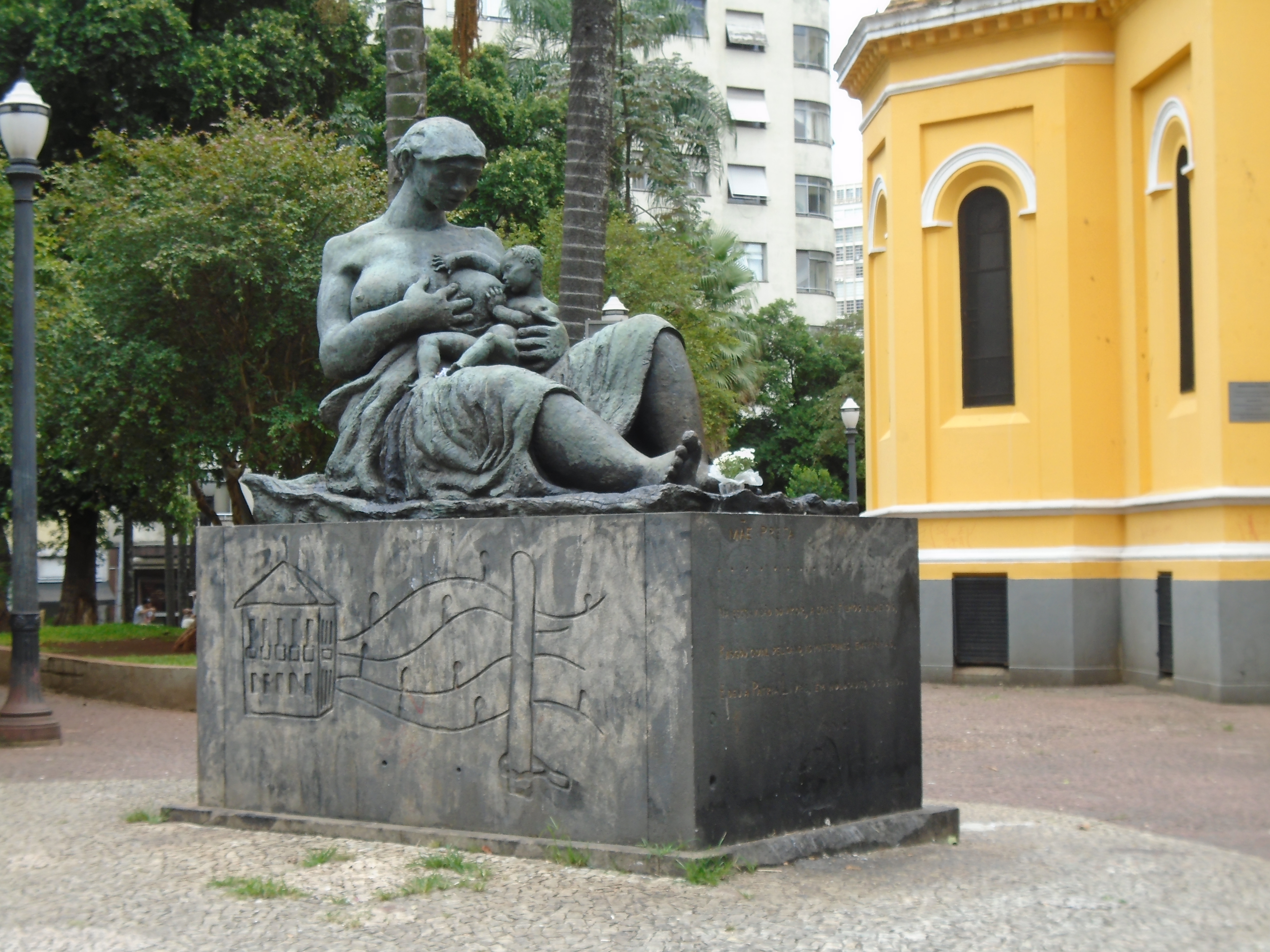 Imagem do monumento "Mãe preta": mulher sentada amamenta bebê. Ela está enrolada em um tecido e seus seios estão descobertos. Fim da descrição